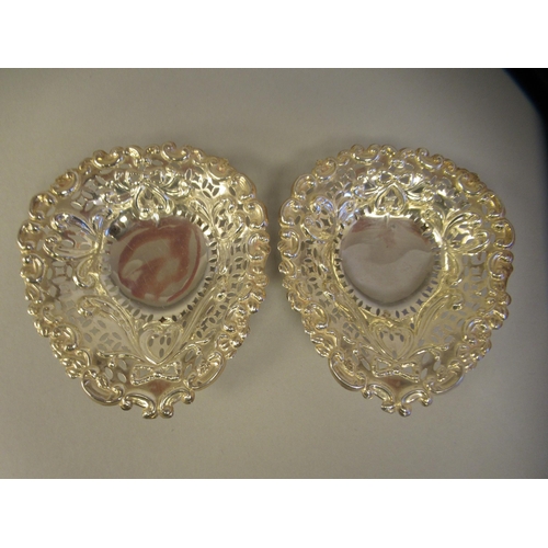 30 - A pair of late Victorian silver heart shape sweet dishes with embossed and pierced decoration, on ba... 