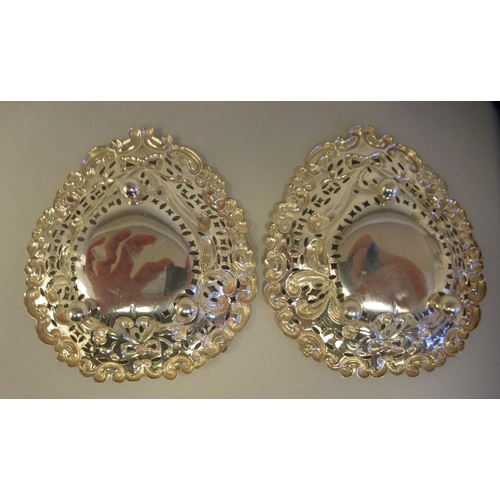 30 - A pair of late Victorian silver heart shape sweet dishes with embossed and pierced decoration, on ba... 