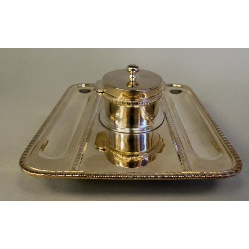 61 - A Georgian style silver standish, the rectangular tray base with a gadrooned border, two pen channel... 