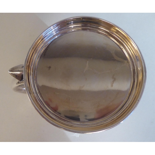 7 - A 19thC style silver mug with an applied wire rim and hollow S-shape handle, on a stepped footrim&nb... 