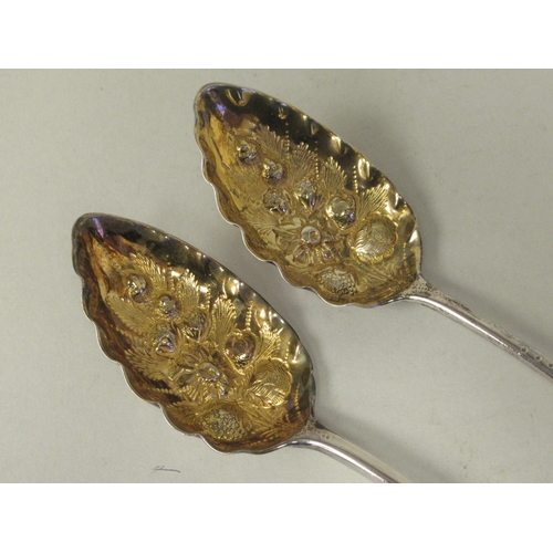 73 - A pair of George III silver and parcel gilt Old English pattern berry spoons with foliate engraved s... 