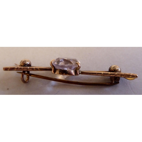 76 - A gold coloured metal golfer's brooch, featuring a pair of golf clubs, two balls and a claw set rose... 