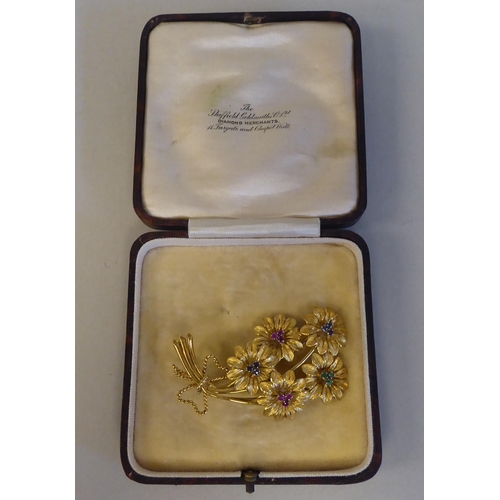 86 - An 18ct textured gold floral brooch, set with coloured stones 