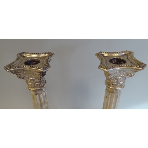 9 - A pair of modern loaded silver candlesticks with detachable bead bordered sconces, Corinthian capita... 