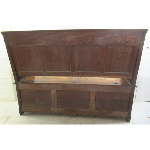 139 - A late Victorian profusely carved oak settle with a high, level, quadruple fielded panelled back and... 