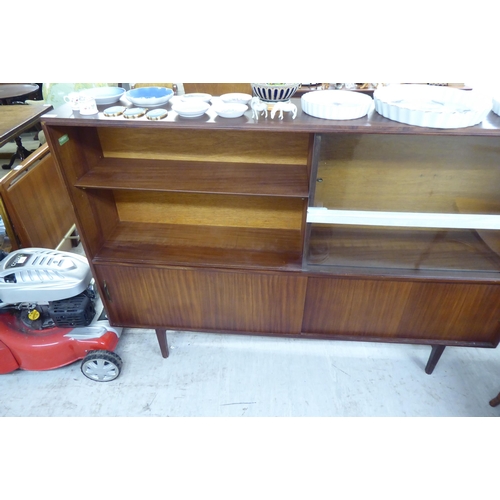 14 - A 1970s 'Multi-Width' teak bookcase with sliding glazed and doors, raised on tapered legs  bears a l... 