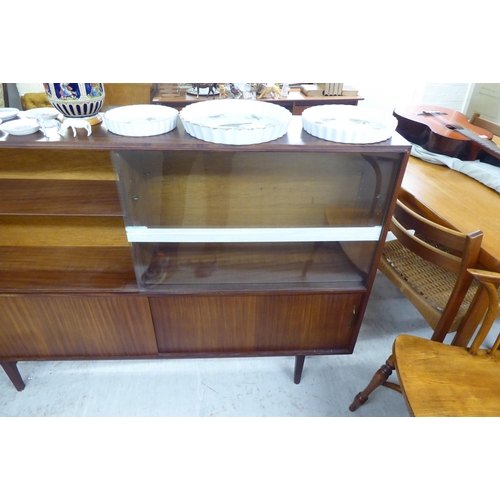 14 - A 1970s 'Multi-Width' teak bookcase with sliding glazed and doors, raised on tapered legs  bears a l... 