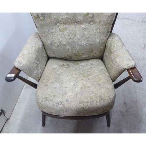 25 - An Ercol dark stained beech and elm framed armchair with floral patterned cushioned fabric back, arm... 