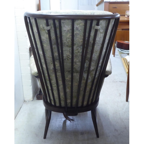 25 - An Ercol dark stained beech and elm framed armchair with floral patterned cushioned fabric back, arm... 
