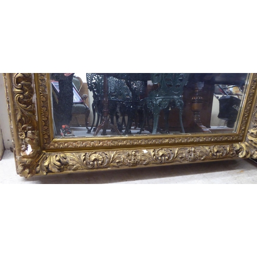 50 - A 19thC mirror, set in a foliate, floral and shell moulded gilt frame  55