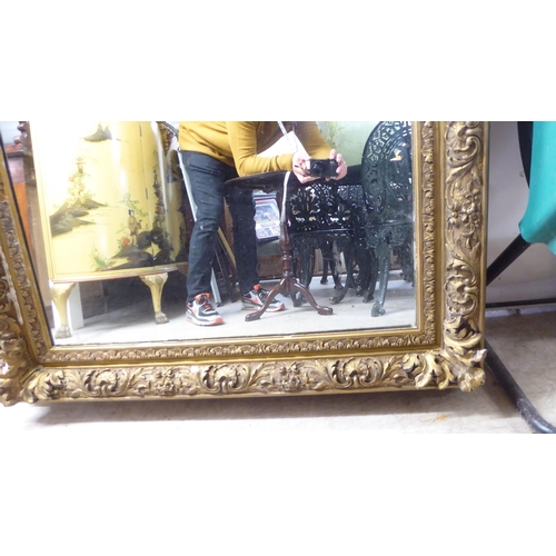 50 - A 19thC mirror, set in a foliate, floral and shell moulded gilt frame  55