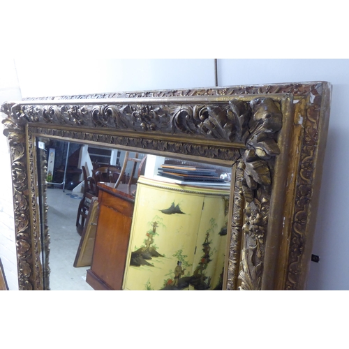 50 - A 19thC mirror, set in a foliate, floral and shell moulded gilt frame  55