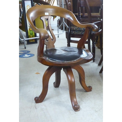54 - A late Victorian mahogany framed, horseshoe shape back desk chair with a simply carved splat and swe... 