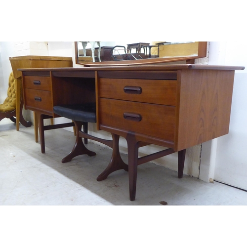 7 - A 1970s teak dressing table surmounted by a rectangular mirror, over four drawers, raised on tapered... 