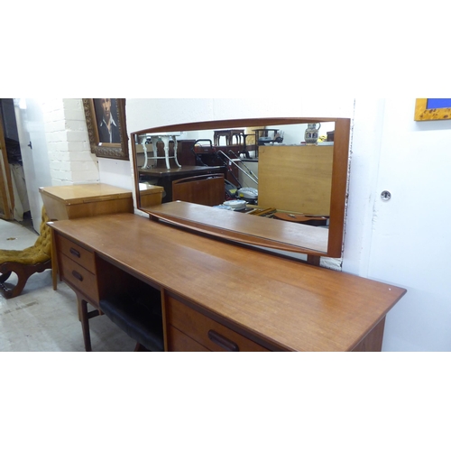 7 - A 1970s teak dressing table surmounted by a rectangular mirror, over four drawers, raised on tapered... 