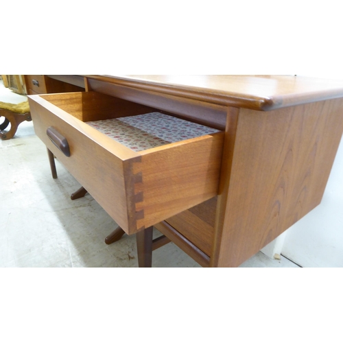 7 - A 1970s teak dressing table surmounted by a rectangular mirror, over four drawers, raised on tapered... 
