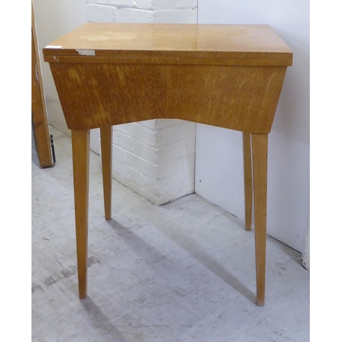 8 - A mid 20thC light oak cased sewing table, raised on square, tapered legs  31