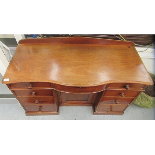 10 - A late Victorian mahogany bow front sideboard, the central, recessed cupboard, flanked by an arrange... 