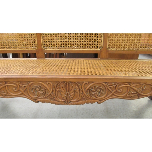 121 - A late 19thC Indian Colonial carved fruitwood framed scroll end settee with a woven split cane panel... 