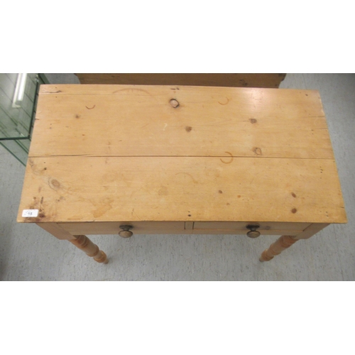 15 - An early 20thC waxed pine side table, the planked top over two inline drawers, raised on ring turned... 