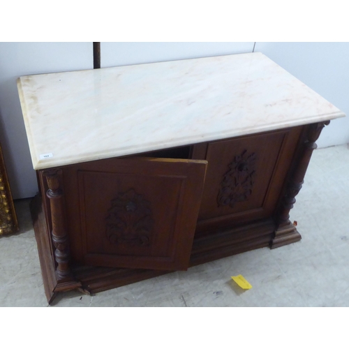 162 - A Continental Edwardian inspired pine side cabinet with a sit-on marble top, over a pair of carved, ... 