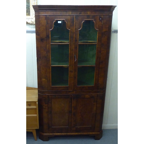 171 - An early 20thC Georgian design walnut corner cabinet with a pair of glazed doors, over a pair of pan... 