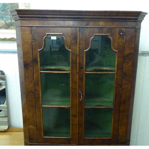 171 - An early 20thC Georgian design walnut corner cabinet with a pair of glazed doors, over a pair of pan... 