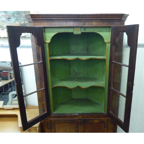 171 - An early 20thC Georgian design walnut corner cabinet with a pair of glazed doors, over a pair of pan... 