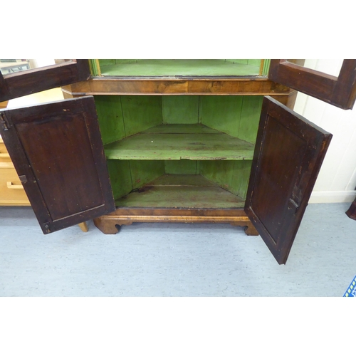 171 - An early 20thC Georgian design walnut corner cabinet with a pair of glazed doors, over a pair of pan... 