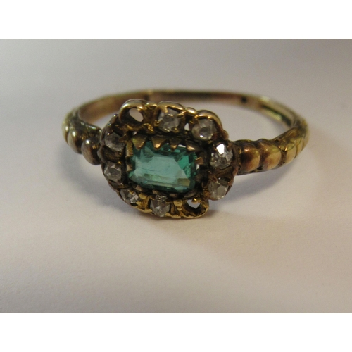 193 - A yellow metal cluster ring, set with a central emerald, surrounded by diamonds (two missing)