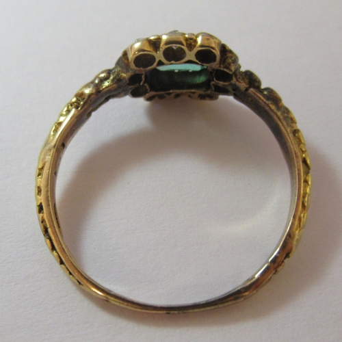 193 - A yellow metal cluster ring, set with a central emerald, surrounded by diamonds (two missing)