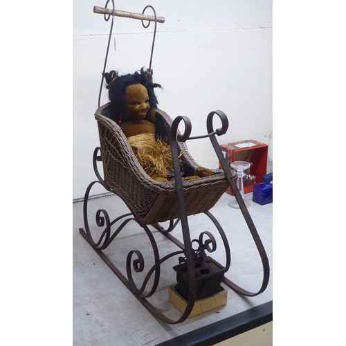 215 - Dolls and accessories: to include a sleigh design wrought iron and woven split cane pram