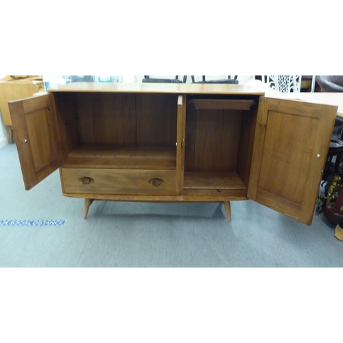 282 - An Ercol blonde elm sideboard with recessed handles, comprising an arrangement of three cupboard doo... 