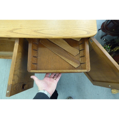 282 - An Ercol blonde elm sideboard with recessed handles, comprising an arrangement of three cupboard doo... 