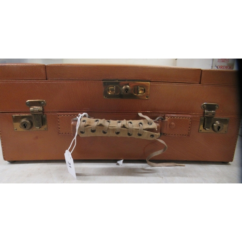 31 - An inter-war period vanity case, in a tan coloured stitched hide with a part fitted interior; and en... 