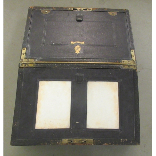 354 - A 19thC black hide clad writing box with a recessed, folding brass handle, the lockable lid with a f... 