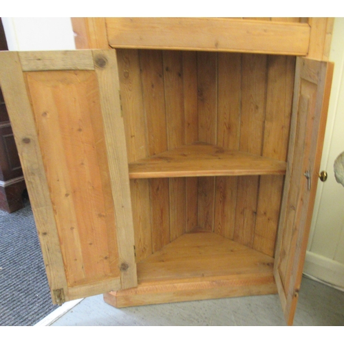 5 - A waxed pine standing corner cupboard, the upper part with open shelves, over two panelled doors&nbs... 