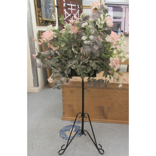 82 - A faux floral display, on a wrought metal stand  52