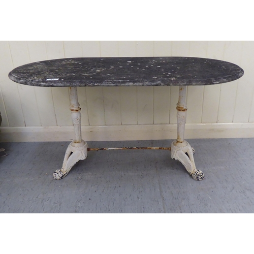 87 - A 20thC terrace table, the weathered stone, oval top on a white painted cast iron underframe  1... 