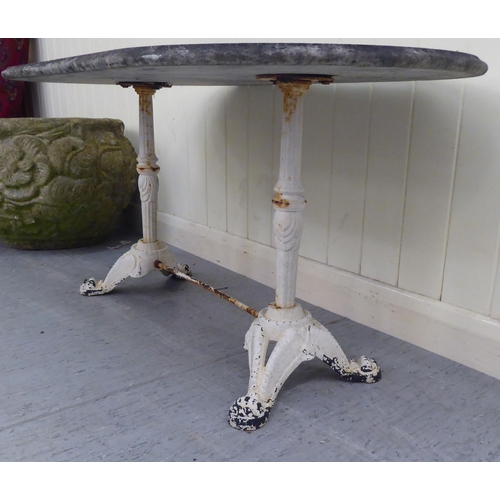 87 - A 20thC terrace table, the weathered stone, oval top on a white painted cast iron underframe  1... 