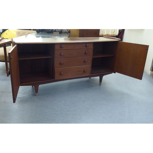 89 - A 1970s teak bow front sideboard with a central bank of four drawers, flanked by two doors, raised o... 