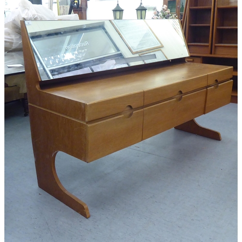 91 - A 1970s teak dressing table, surmounted by an angled mirror, over six drawers, raised on panelled en... 