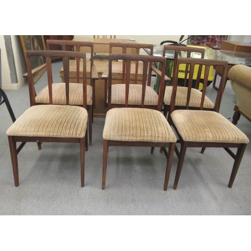 97 - A set of six 1970s teak framed dining chairs, the fabric upholstered seats raised on tapered legs  c... 