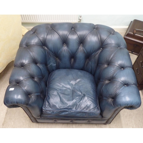 143 - A modern Chesterfield style  enclosed armchair, part button and stud upholstered in blue hide