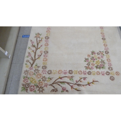 276 - A modern woollen rug, decorated with flora, on a cream coloured ground  74