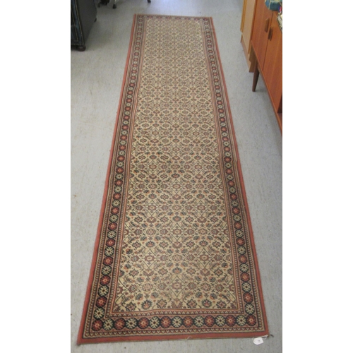 79 - A machine made Persian design runner, decorated with repeating floral designs, on a multi-coloured g... 