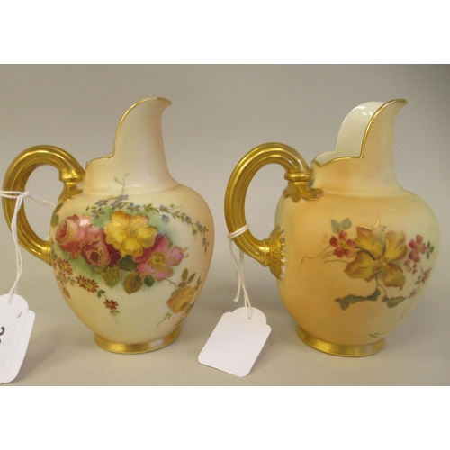 69 - A pair of Royal Worcester blush ivory glazed and gilded china flatback jugs, decorated with mixed fl... 