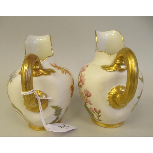 74 - A pair of Royal Worcester blush ivory glazed and gilded china flatback jugs, decorated with mixed fl... 