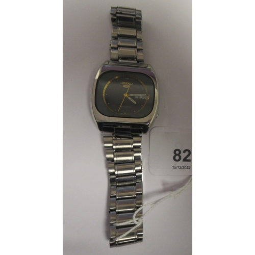 82 - A vintage Seiko 5 automatic, stainless steel cased bracelet wristwatch, faced by a black and gilt ba... 