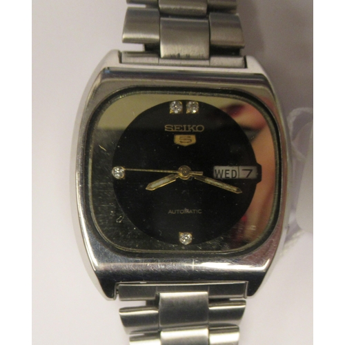 90 - A vintage Seiko 5 automatic stainless steel cased bracelet watch, faced by a black dial with a day a... 